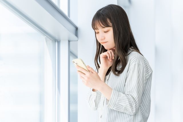 スマホを見て考える女性